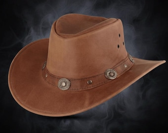 Könnte beinhalten: Ein brauner Cowboyhut aus Leder mit breiter Krempe und runder Krone. Der Hut hat dekorative silberfarbene Conchos und Nieten um die Krone. Der Hut ist im klassischen Western-Stil gehalten.