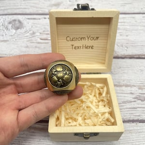 May include: A gold-toned ring with a detailed design, including a yin-yang symbol and dragon patterns. The ring is presented in an open wooden box, with the engraved text "Custom Your Text Here" on the lid. The box contains shredded paper.