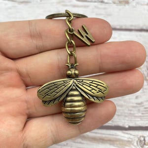 Pu&ograve; includere: Un portachiavi a forma di ape color bronzo con un ciondolo a forma di lettera "W". Il ciondolo a forma di ape presenta ali e segmenti del corpo dettagliati, attaccati a una catena e a un portachiavi. Il portachiavi &egrave; rifinito con un aspetto antico.