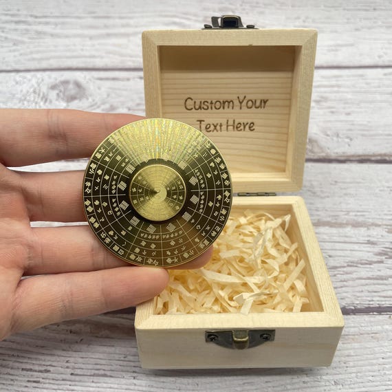 A precision-machined brass compass spinner in a custom wood box — where fidget toy meets Zen artifact meets heirloom office piece.