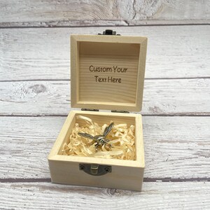 May include: A small, open wooden box with a hinged lid. Inside, a silver-colored bee figurine rests on shredded paper. The box's interior lid has the text "Custom Your Text Here" engraved. The box is unpainted and has a natural wood grain.