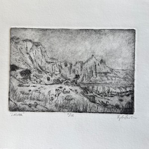 May include: A monochrome etching print titled "Dakota" showing a landscape with craggy rock formations and minimal vegetation. The print is numbered 7/15 and signed. The artwork is mounted on white paper.