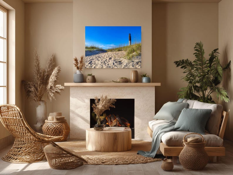 Peut inclure: Un salon sur le th&egrave;me c&ocirc;tier avec un tableau encadr&eacute; d'un phare sur un sentier sablonneux sous un ciel bleu. La pi&egrave;ce comprend une chaise en osier, une table basse en bois et une palette de couleurs neutres avec des plantes et des coussins d&eacute;coratifs.