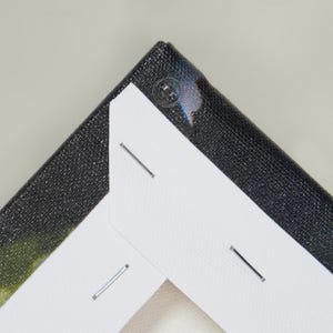 Peut inclure: Gros plan sur un coin d'impression sur toile. La toile est tendue sur un cadre en bois et fix&eacute;e avec des agrafes. La toile a une surface noire textur&eacute;e. Le coin est renforc&eacute; par un bouton en plastique transparent.