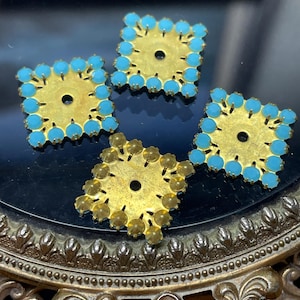 May include: Four square-shaped, gold-toned metal components with a central hole. Three are adorned with turquoise-colored, round embellishments around the edges. The fourth has similar embellishments in a yellow-gold color.