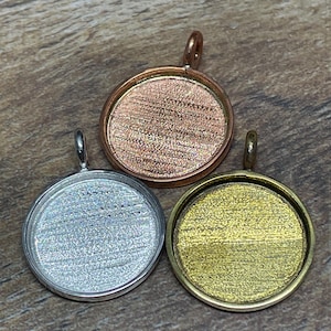 May include: Three round pendant trays in copper, silver, and gold tones. Each tray has a loop for attaching to a chain or cord. The trays are empty, ready for custom inserts. Ideal for jewelry making and crafting.