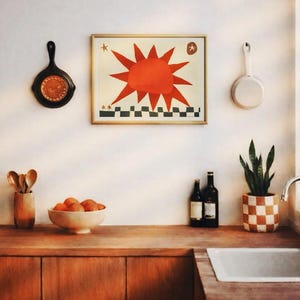 Peut inclure: Int&eacute;rieur de cuisine avec plan de travail et placards en bois. Une &oelig;uvre d'art encadr&eacute;e avec un soleil rouge est accroch&eacute;e au mur. Il y a un bol d'oranges, des bouteilles de vin et un pot de plante &agrave; carreaux.