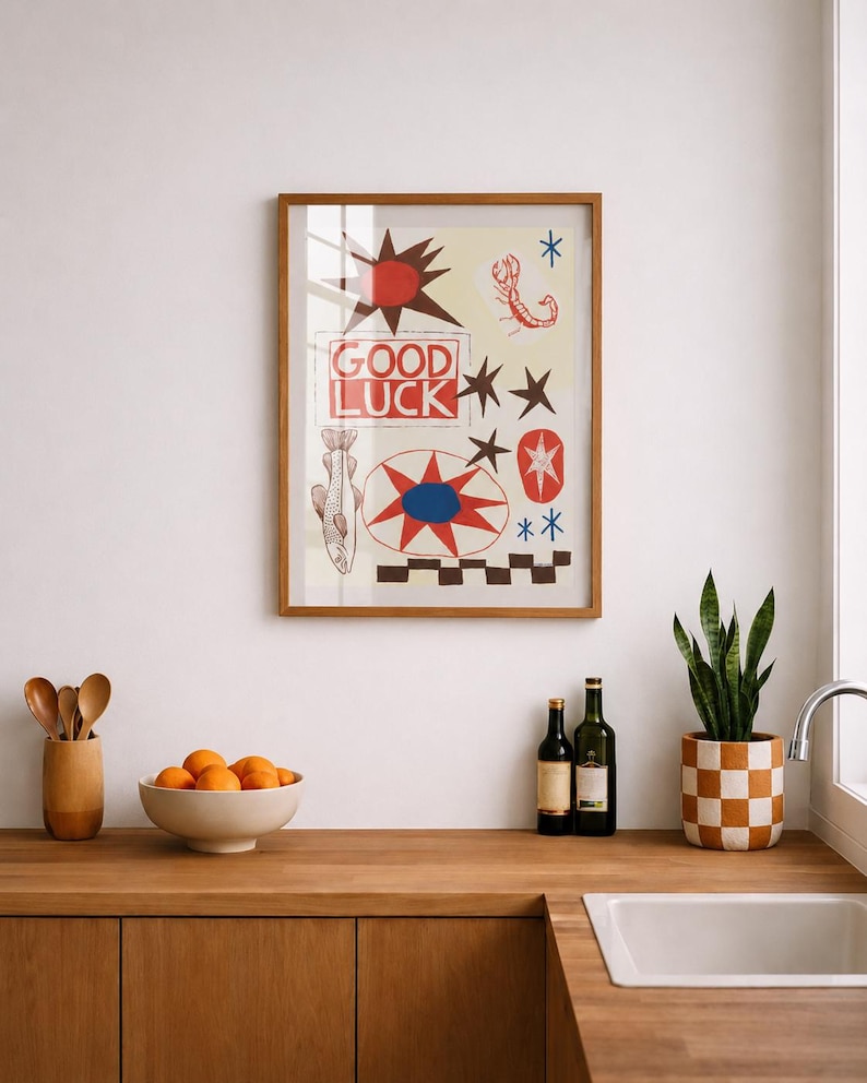 Puede incluir: Una l&aacute;mina de arte mural enmarcada con el texto GOOD LUCK en letras rojas. El dise&ntilde;o incluye un sol rojo, un escorpi&oacute;n, un pez, estrellas y un patr&oacute;n de cuadros en colores rojo, azul, negro y crema, todo dentro de un marco de madera.