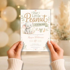 Peut inclure: Une carte d'invitation pour une fête prénatale avec un éléphant en dessin animé, une corde à linge avec un body et une cacahuète, et le texte Our Little Peanut is on the way, Megan Whitmore, July 07, 2024, The Whitmore Home, 123 Orange Grove Lane, Boulder, CO.