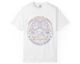 Puede incluir: Camiseta blanca con un diseño gráfico circular en rojo, blanco y azul. El diseño presenta un águila, estrellas y el texto "UNITED STATES OF AMERICA", "1776", "2026" y "250 YEARS FOUNDATION OF FREEDOM".
