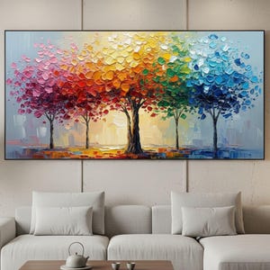 May include: A large, rectangular oil painting depicts five trees with vibrant, textured foliage in a spectrum of colors. The artwork features a black frame and is displayed above a white sectional sofa and a wooden coffee table.