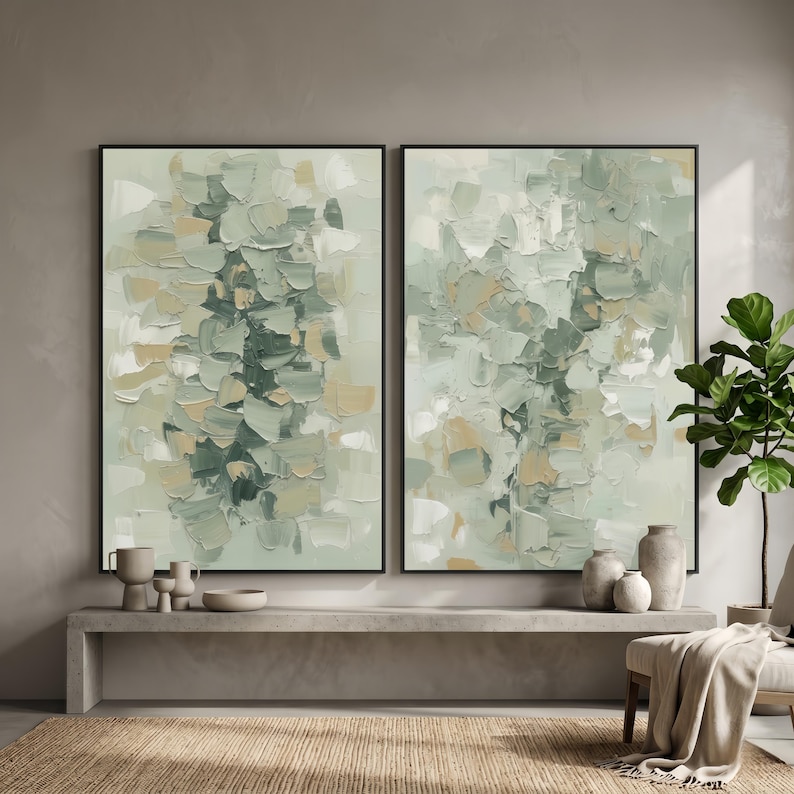 May include: Two framed abstract paintings with a textured, layered appearance. The artwork features a palette of muted greens, beige, and white, creating a soft, natural aesthetic. The paintings are displayed above a concrete bench with decorative vases.