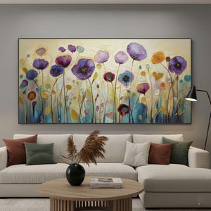 May include: An abstract floral painting featuring a field of stylized flowers in shades of purple, blue, and orange against a textured yellow background. The artwork is framed in black and hangs above a white sectional sofa.