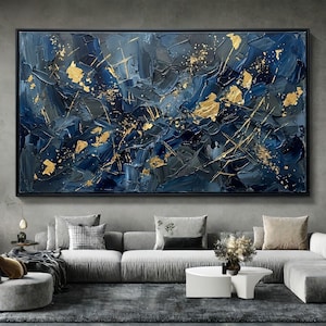 May include: Abstract oil painting on canvas, featuring a textured, dark blue and gray background with gold leaf accents. The artwork is framed in a black rectangular frame, suitable for home decor.