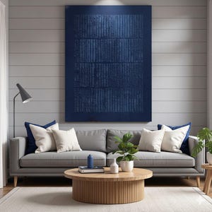 Könnte beinhalten: Ein modernes Wohnzimmer mit einem grauen Sofa, weißen und marineblauen Kissen und einem großen abstrakten Kunstwerk in Marineblau. Ein runder Couchtisch aus Holz und Pflanzen ergänzen die Einrichtung. Der Raum wird von einer Stehlampe beleuchtet.