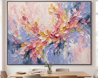 May include: A large rectangular wall painting featuring thick, textured impasto brushstrokes in shades of soft pink, pale yellow, and periwinkle blue. The abstract composition displays swirling, petal-like marks that create a sense of movement across the canvas, framed in a thin black border.