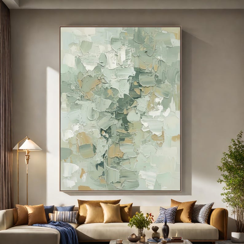 May include: Large abstract painting with a textured surface. The artwork features a palette of soft greens, whites, and beige tones, applied in thick brushstrokes. The painting is framed and hangs above a sofa with decorative cushions.