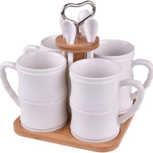 Può includere: Un set da tè in ceramica bianca con quattro tazze, cucchiai e un supporto. Le tazze hanno un design a forma di bambù e sono disposte su un vassoio di legno. I cucchiai sono tenuti in un supporto centrale di legno con un manico in metallo.
