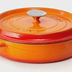 Könnte beinhalten: Ein orangefarbener emaillierter gusseiserner Dutch Oven mit Deckel. Der Deckel hat einen silbernen Griff und das Wort "LAVA" ist auf dem Deckel geprägt. Der Topf hat zwei Griffe und ist zum Kochen geeignet.