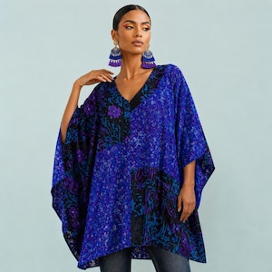 May include: A loose-fitting, V-neck tunic top featuring a vibrant patchwork design in shades of royal blue, purple, and black. The garment displays a mix of floral and abstract patterns across its flowing, wide-sleeved silhouette.