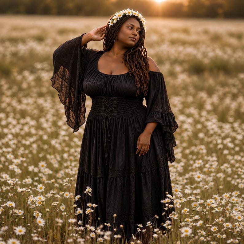 May include: A black dress featuring a scoop neckline, cold-shoulder design, and long, flared sleeves with ruffled edges. The bodice includes a corset-style lace-up front detail with a smocked waist, and the skirt has a tiered, flowing silhouette.
