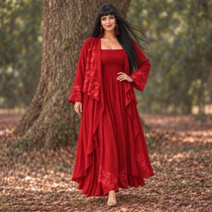 May include: A vibrant red floor-length dress featuring a square neckline and a smocked bodice, paired with a matching long-sleeved open cardigan that has intricate tonal lace detailing along the front panels and the wide sleeve cuffs.