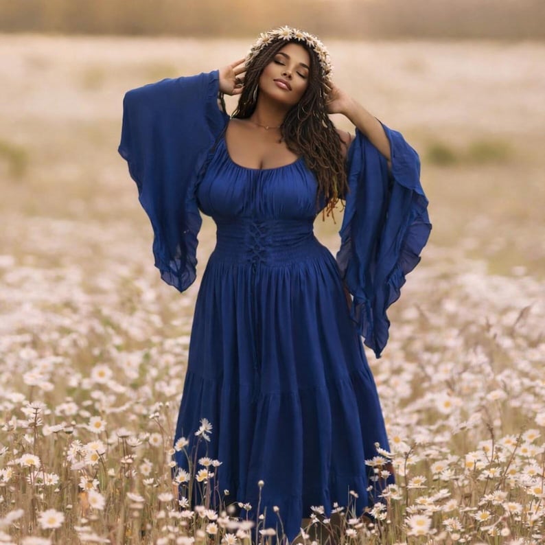 May include: A royal blue midi dress featuring a scoop neckline, long flared bell sleeves, and a corset-style lace-up bodice with a smocked waist. The skirt is gathered and tiered, falling to a mid-calf length, complemented by a floral crown.