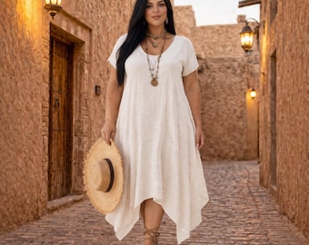 Könnte beinhalten: Eine Frau trägt ein cremefarbenes Kleid mit kurzen Ärmeln und asymmetrischem Saum. Sie hält einen Strohhut und trägt mehrschichtige Halsketten und Sandalen. Der Hintergrund ist eine gepflasterte Gasse mit Steinmauern und Laternen.