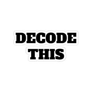 May include: A white sticker with the words "DECODE THIS" in bold, black, sans-serif font. The text is arranged in two lines, with "DECODE" above "THIS". The sticker has a black border.