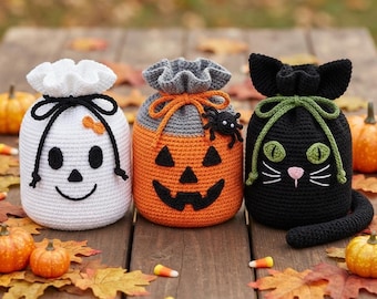 May include: Three crocheted drawstring bags featuring Halloween designs. The left bag is white with a black ghost face and bow. The center bag is orange and gray with a jack-o'-lantern face and spider. The right bag is black with a cat face and tail.