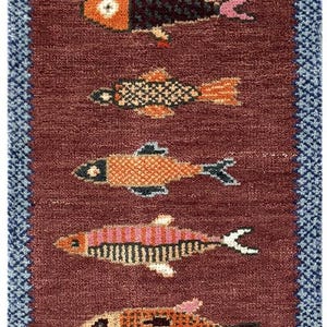 Op de afbeelding: Een rechthoekig tapijt met een bordeauxrode achtergrond en een herhalend patroon van kleurrijke vissen. De vissen zijn in verschillende kleuren, waaronder roze, oranje en blauw, en hebben gedetailleerde patronen. Het tapijt heeft een blauwe rand.