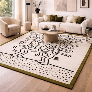 Puede incluir: Una alfombra rectangular con un fondo crema y un dibujo lineal negro de figuras estilizadas. La alfombra tiene un borde verde y está colocada en una sala de estar con un sofá blanco y suelo de madera.