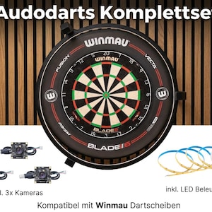 Może przedstawiać: Czarno-czerwona tarcza do darta Winmau z zielono-białym celem. Zestaw zawiera trzy kamery i oświetlenie LED. Tekst "Audodarts Komplettset" znajduje się na górze. Kompatybilny z tarczami Winmau.
