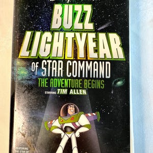 May include: A VHS tape for Disney Pixar's "Buzz Lightyear of Star Command: The Adventure Begins," starring Tim Allen. The cover features Buzz Lightyear in his space suit against a starry background, with the Toy Story logo.