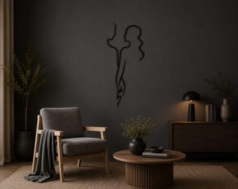 May include: A black metal wall art piece featuring a continuous line drawing of two human profiles facing each other, with one figure's hand reaching toward the other. The minimalist sculpture is mounted on a dark gray wall above a wooden chair.