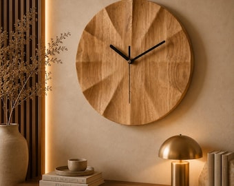 May include: A circular wall clock made of light brown wood with a faceted, geometric surface texture. The clock features three thin, black metal hands positioned at the center. The wood grain is visible across the entire face of the clock.