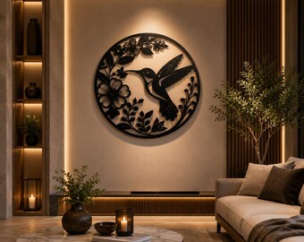 May include: A circular black metal wall art piece featuring a cutout design of a hummingbird in flight surrounded by flowers and leaves. The artwork is mounted on a light-colored wall, showcasing intricate silhouettes of floral and avian motifs.