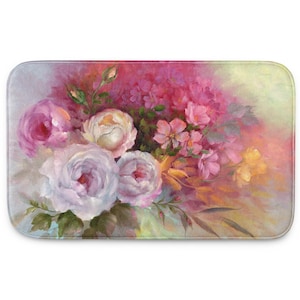 May include: Rectangular bath mat featuring a floral design. The image showcases a bouquet of roses in shades of pink, white, and yellow, with green foliage. The background has a soft, blended effect with hues of pink and yellow.
