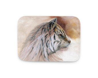 May include: A rectangular bath mat featuring a watercolor painting of a tiger's head in profile. The tiger has white fur with black stripes and orange eyes. The background is a blend of brown and beige.