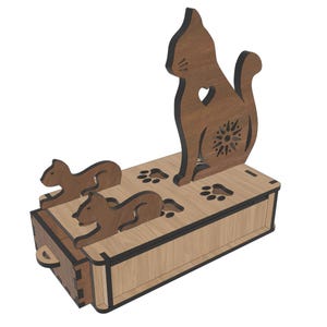 Puede incluir: Una caja de madera con temática de gatos con una silueta de gato en la parte superior y dos siluetas de perros en la parte delantera. El gato tiene un recorte de corazón y un diseño de sol. Huellas de patas están grabadas en la parte superior.