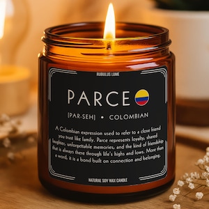 May include: A lit soy wax candle in an amber glass jar with a black label. The label features the text PARCE, a Colombian flag icon, the phonetic pronunciation, and a definition describing the term as a Colombian expression for a close friend.