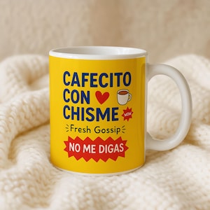 May include: A white ceramic coffee mug with a yellow exterior. The mug features the text "CAFECITO CON CHISME" in blue, a red heart, a coffee cup graphic, and the words "Fresh Gossip" and "NO ME DIGAS".