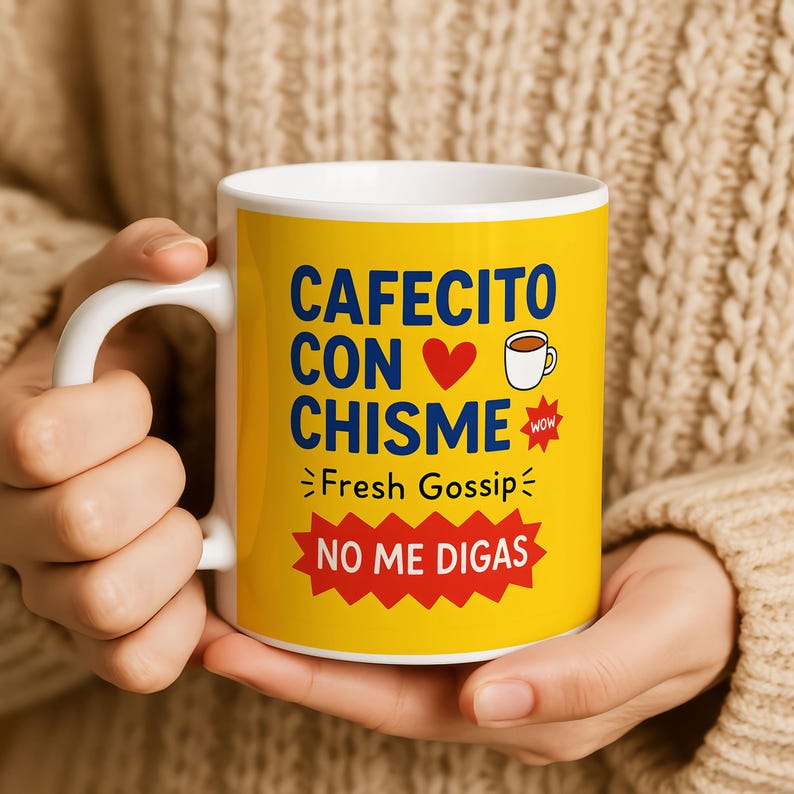 May include: A white ceramic coffee mug with a yellow background. The mug features the text "CAFECITO CON CHISME" with a heart and coffee cup graphic. Below the text is "Fresh Gossip" and "NO ME DIGAS" in a red starburst.