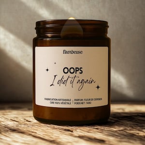 Peut inclure: Une bougie en pot de verre marron avec une étiquette blanche. L'étiquette indique "flambeuse" en haut, avec "OOPS I did it again" en écriture manuscrite en dessous. La bougie est étiquetée "FABRICATION ARTISANALE, CIRE 100% VEGETALE, POIDS NET: 140G".