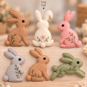 May include: Six felt rabbit ornaments in tan, cream, pink, light grey, light brown, and sage green. Each rabbit features a black circular eye and embroidered leaf or flower details. The text SVG Pdf is visible at the top centre of the image.