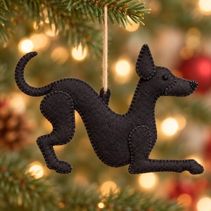 May include: A black felt dog ornament shaped like a greyhound in a play bow position. The ornament features visible stitched edges and is suspended by a thin tan twine loop attached to the top of the dog's back for hanging purposes.