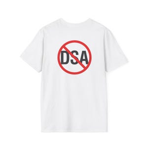 Può includere: Una t-shirt bianca a maniche corte con una grafica sul petto. La grafica consiste in un cerchio rosso con una linea diagonale, sovrapposto al testo nero DSA, creando un simbolo di divieto universale sopra le lettere.