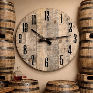 May include: A large, round wooden wall clock with black numerals and hands. The clock is made from reclaimed wood and has a rustic, weathered appearance. The clock is mounted on a beige wall. The clock is surrounded by wooden barrels.