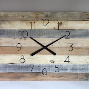 May include: Square wooden wall clock with a rustic design. The clock face is made of horizontal wooden planks in shades of brown, gray, and beige. Black numerals mark the hours, and black hands indicate the time. A decorative piece for any room.