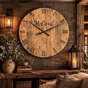 May include: A large, round wooden clock with black Roman numerals and hands, mounted on a rustic wooden wall. The clock face features the name "McCord" in a script font. The scene includes a lit lantern and decorative elements.